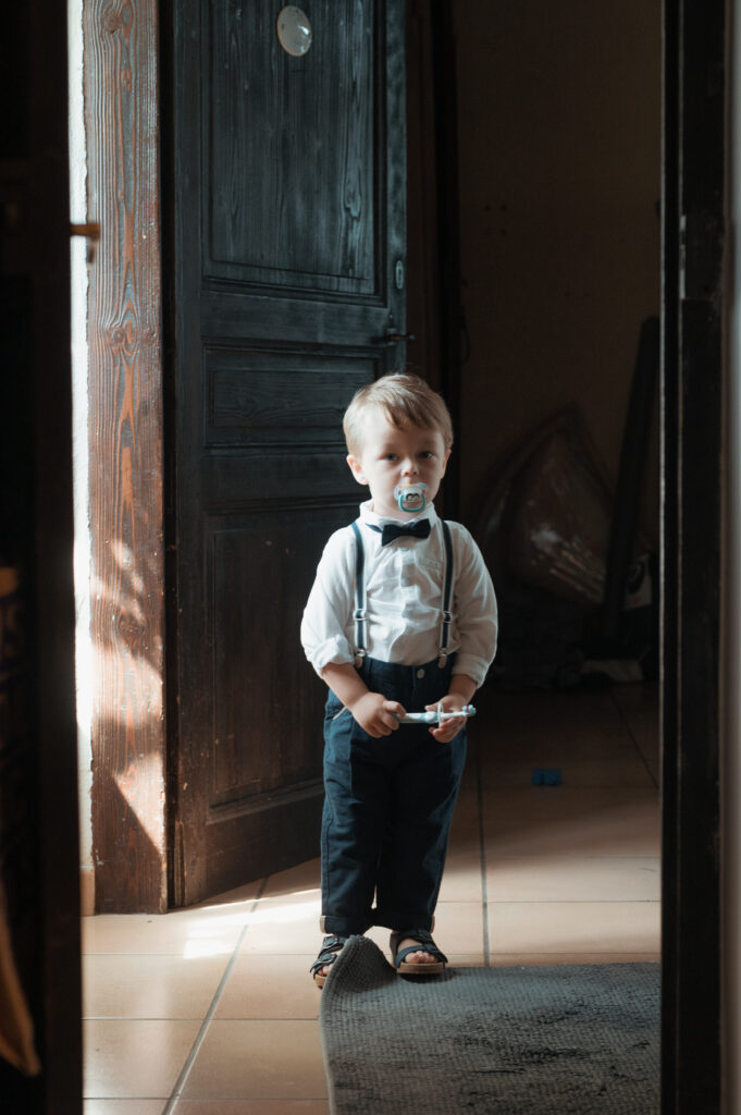 Petit garçon en costume avec bretelles et nœud papillon lors des préparatifs d'un mariage dans l'Ain