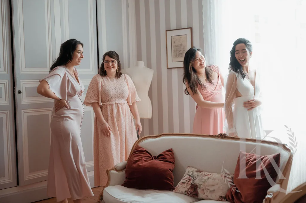 Quatre demoiselles d'honneur en robes roses et blanches souriantes dans chambre élégante