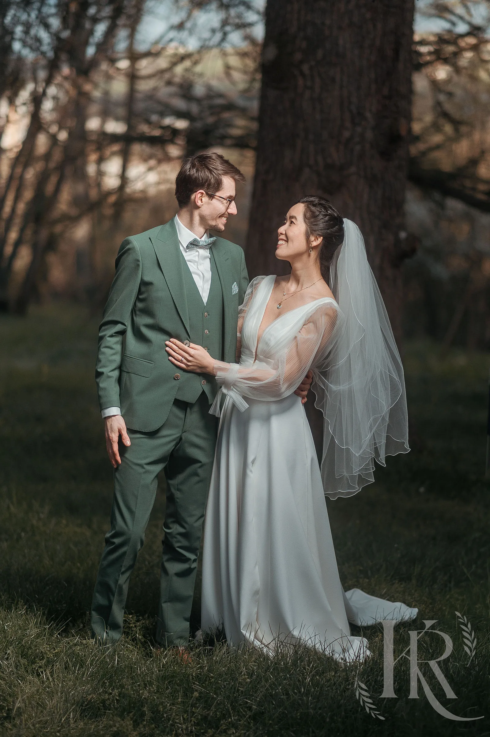 Portrait des mariés Wing Yan et Arthur dans le jardin naturel du Domaine de Tourieux, lumière dorée de fin de journée