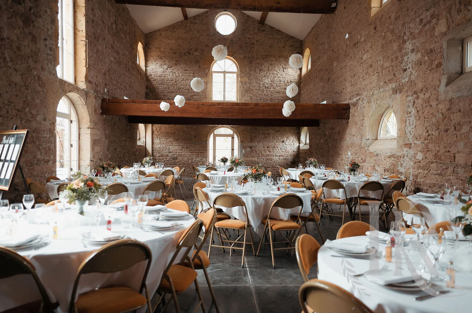 Salle de réception du mariage en pierre brute au Domaine de Tourieux, tables dressées avec élégance