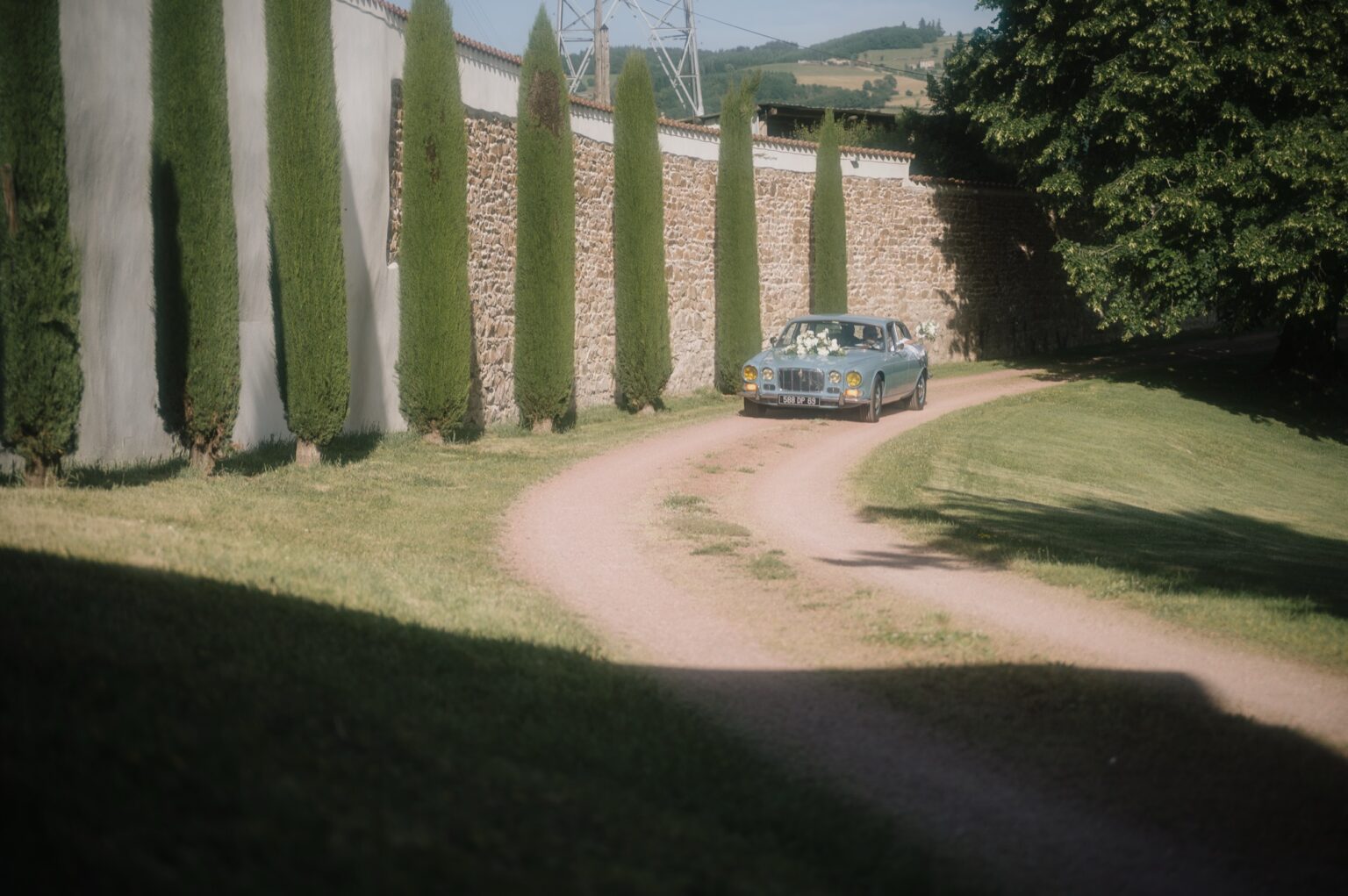 Voiture ancienne des mariés dans l'allée de cyprès, Château de Laforest à Thizy-les-Bourgs, Kaïto Rimbaud photographe
