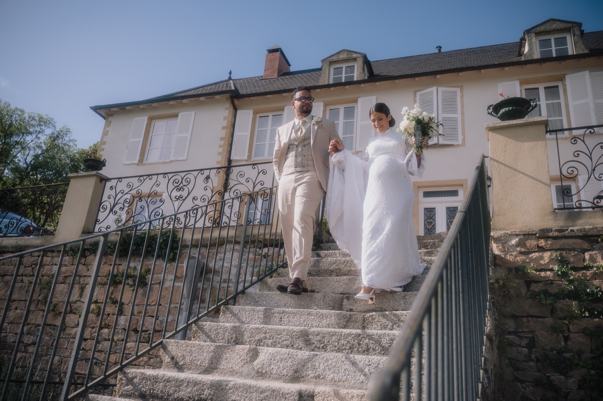 Les mariés descendent les marches vers leurs invités au Château de Laforest, mariage à Thizy-les-Bourgs