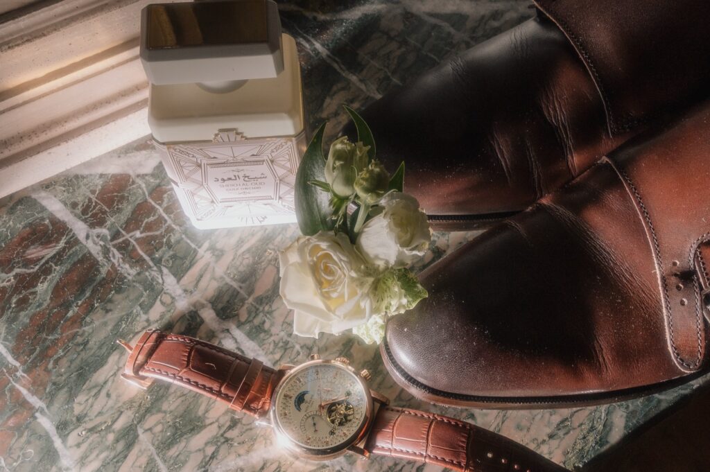 Flatlay des détails du marié, montre Patek, parfum, boutonnière et chaussures, mariage au Château de Laforest, Thizy-les-Bourgs