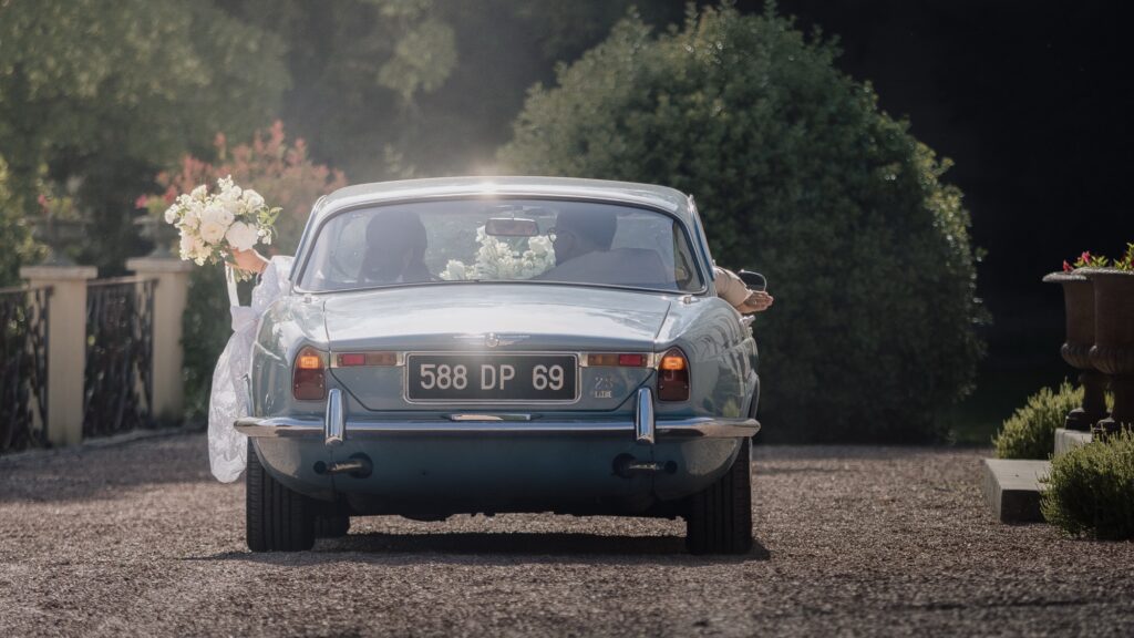 La Jaguar des mariés à contre-jour à l'arrivée au domaine, mariage au Château de Laforest, Thizy-les-Bourgs