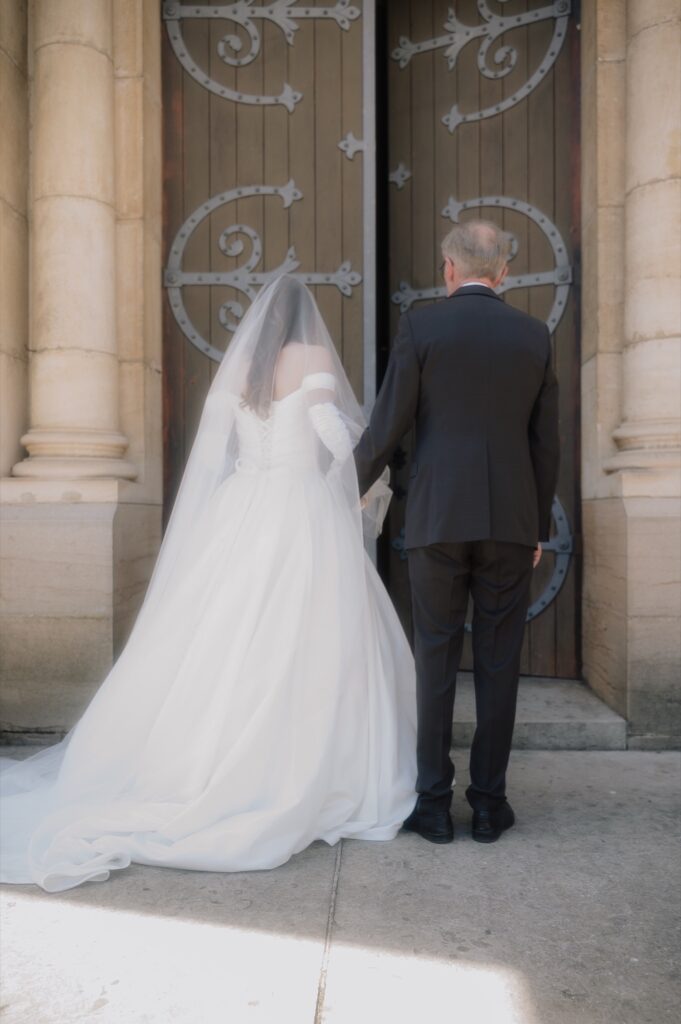 La mariée et son père devant les portes de l'église du Perréon avant l'entrée, Beaujolais, Kaïto Rimbaud photographe