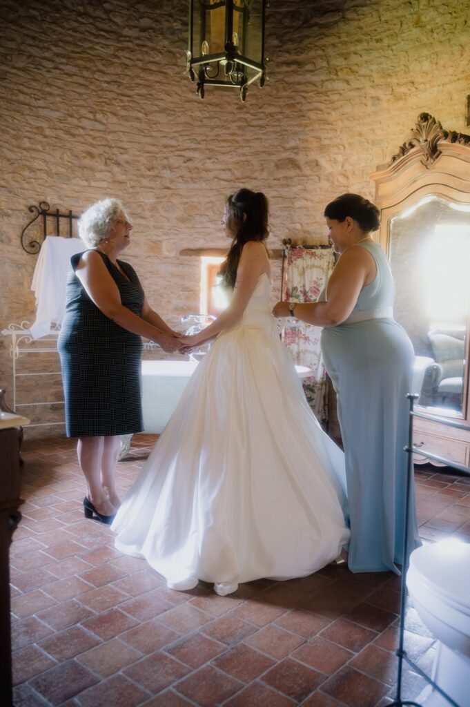 La mère de la mariée lui tient les mains pour la rassurer pendant l'enfilage, mariage au Château du Sou, Lacenas