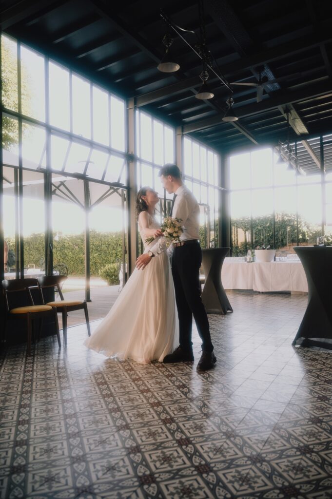 Photo de couple des mariés dans la verrière du Fourvière Hôtel à contre-jour, mariage à Lyon