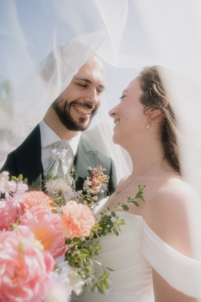 Portrait des mari&eacute;s sous le voile avec le bouquet color&eacute;, mariage au Ch&acirc;teau du Sou, Lacenas, lumi&egrave;re argentique
