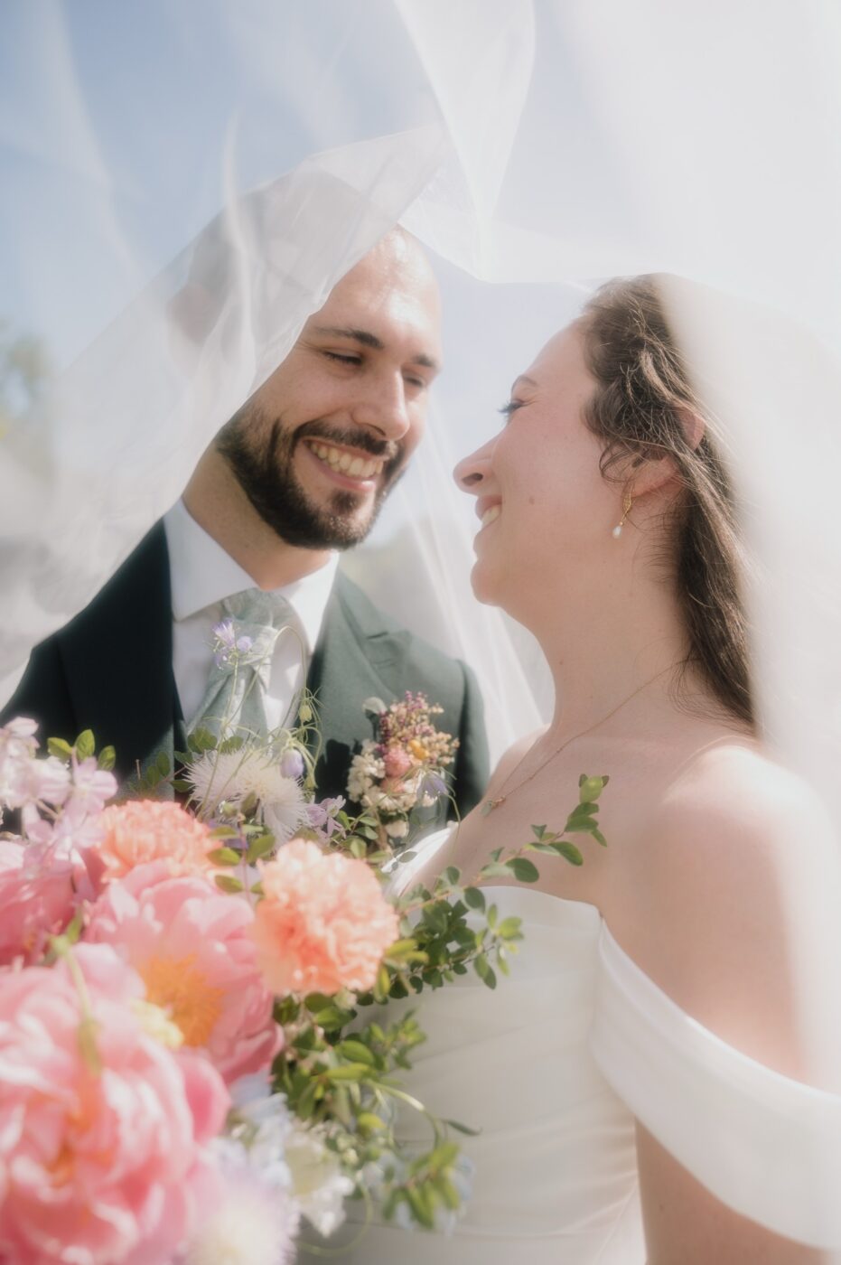 Portrait des mariés sous le voile avec le bouquet coloré, mariage au Château du Sou, Lacenas, lumière Portra 400