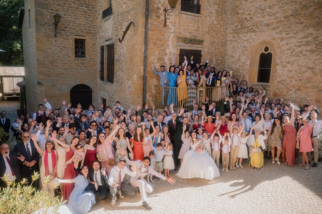 Photo de groupe de tous les invités devant le Château du Sou, mariage à Lacenas, Beaujolais, Kaïto Rimbaud photographe
