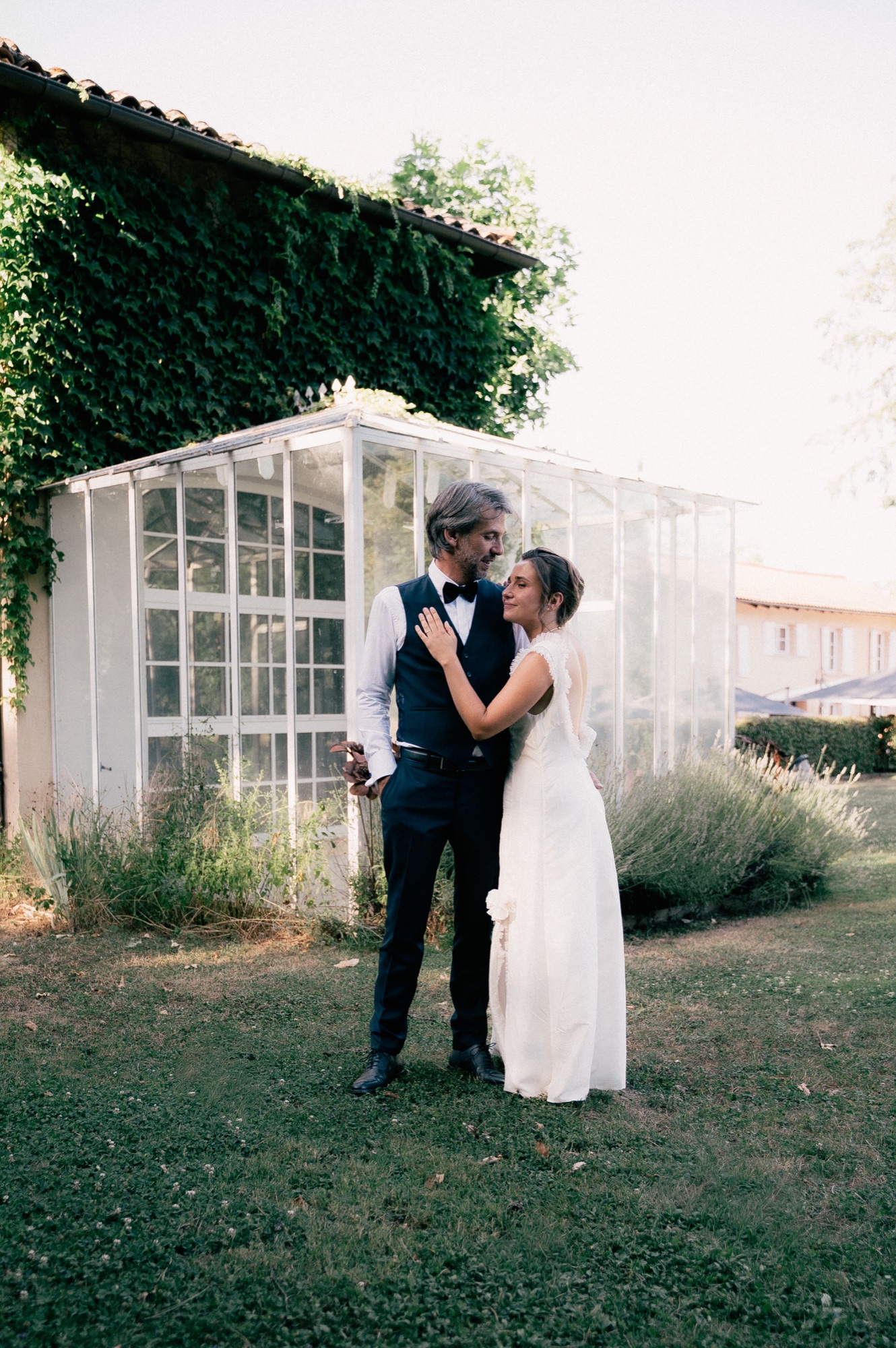 Couple de mariés enlacés devant une verrière à l'heure dorée, Kaïto Rimbaud photographe