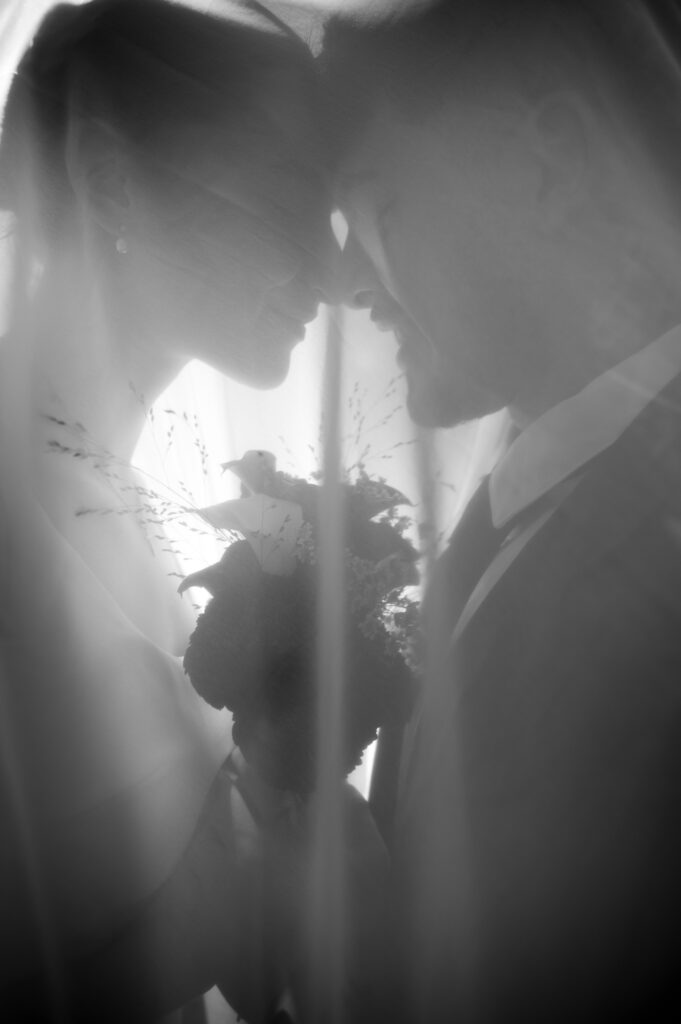 Couple de mariés sous le voile à contre-jour, noir et blanc, Kaïto Rimbaud photographe de mariage